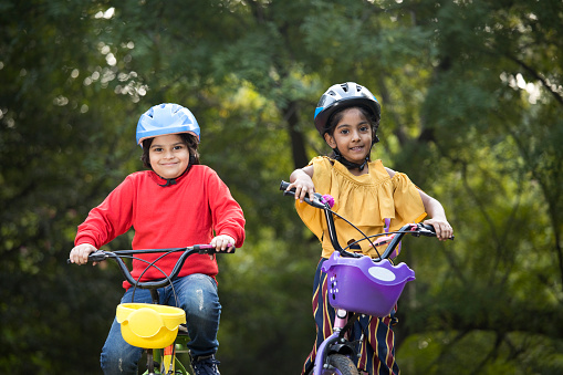 Carefree brother and sister riding bicycle at park