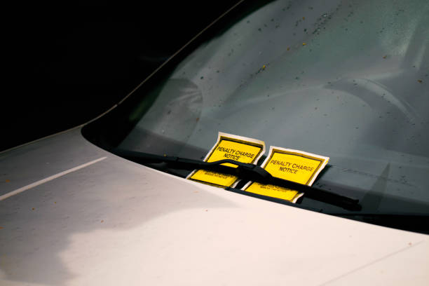 istock Two bright yellow parkings ticket tucked under the windscreen/windshield wiper. 1196822427