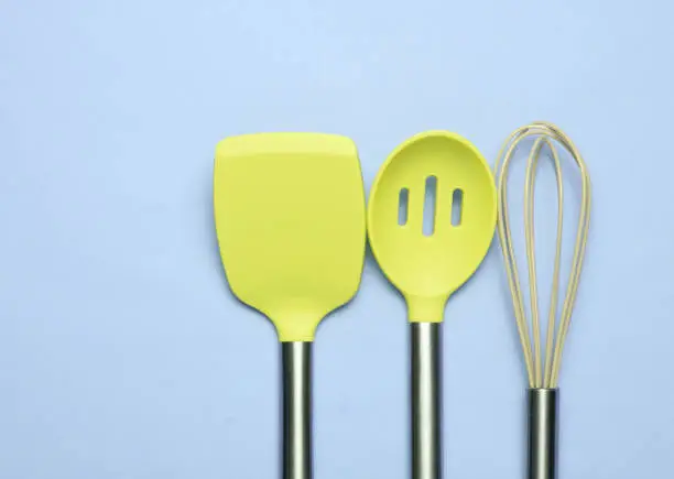 Set of tools for cooking on pink background. Silicone paddles with metal handles, whisk. Top view. Copy space."n