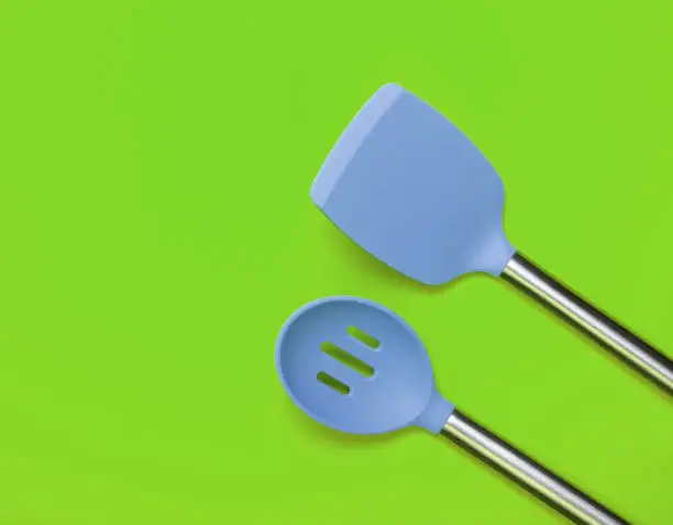 Set of tools for cooking on green background. Silicone paddles with metal handles. Top view. Copy space.