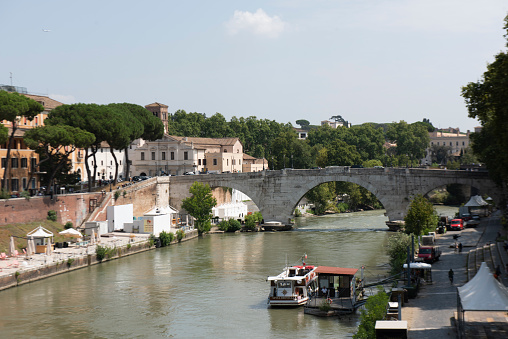 People walking in the Tiber riverside next to the Ponte Cestio (Pons Cestius) and the Tiber Island at Rome city, Italy.