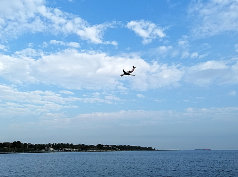 Istanbul, Turkey - October 28, 2019: A plane above Marnara Sea people are near by sea side of Florya. People are cycling and walking in a sunny day near by sea side of Florya.