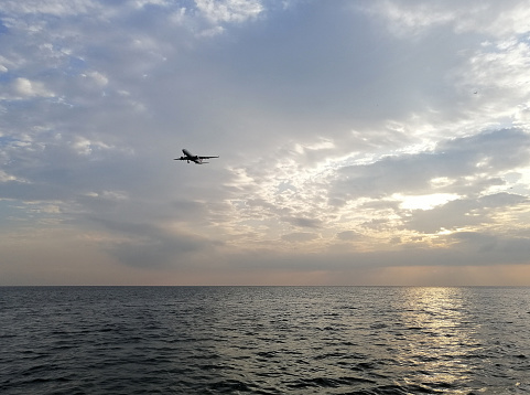 Istanbul, Turkey - October 28, 2019: A plane above Marnara Sea people are near by sea side of Florya. People are cycling and walking in a sunny day near by sea side of Florya.