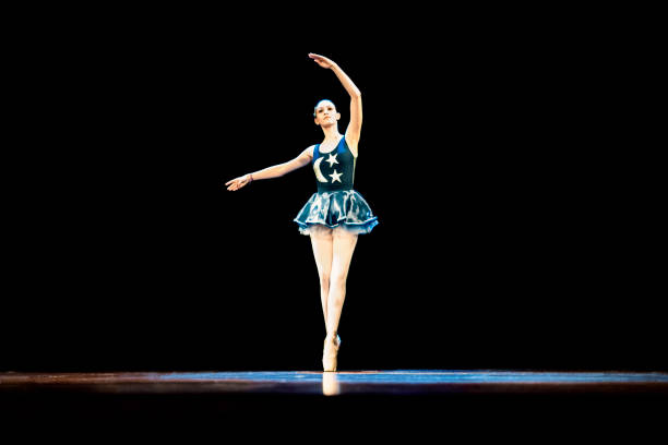 istock Young girl dancing ballet on a dark stage 1196848599