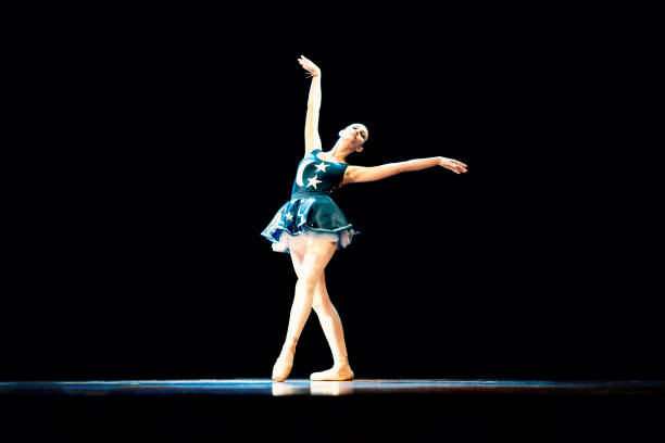 istock Young girl dancing ballet on a dark stage 1196848600
