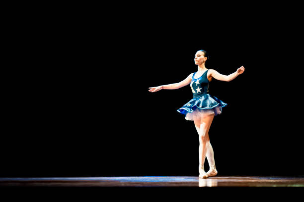 istock Young girl dancing ballet on a dark stage 1196848601