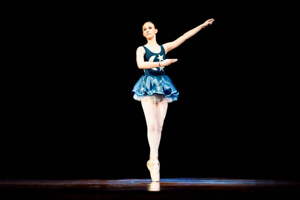 istock Young girl dancing ballet on a dark stage 1196848621