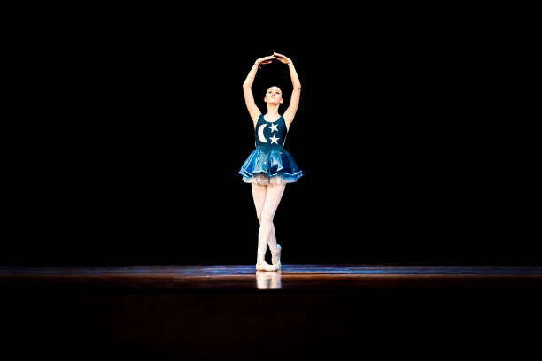 istock Young girl dancing ballet on a dark stage 1196848632