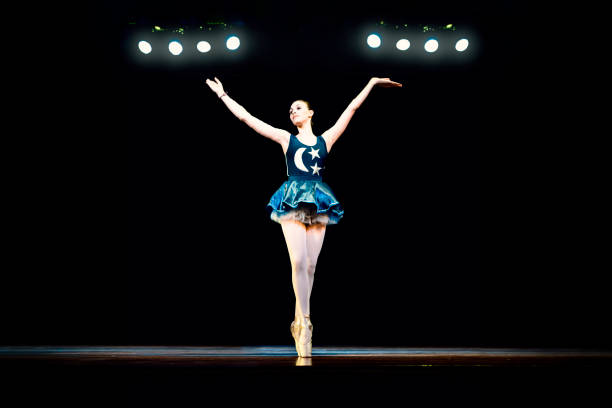 istock Young girl dancing ballet on a dark stage 1196849142