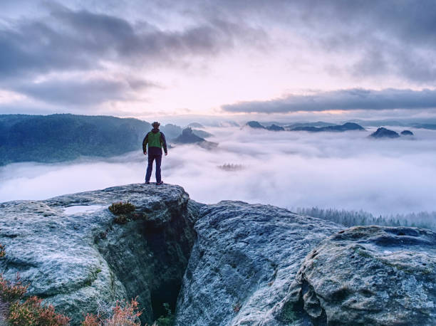 istock Men on mountain enjoy aerial view, arms raised over clouds 1196852300