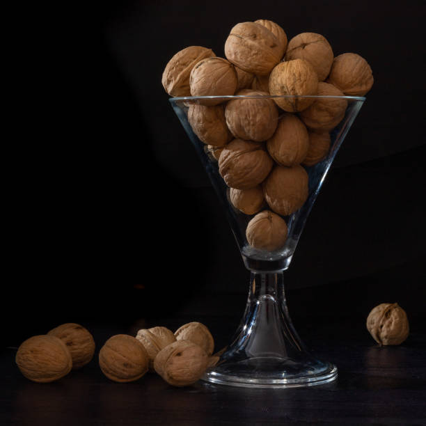 istock Glass dish with walnuts on a black background. 1196857600