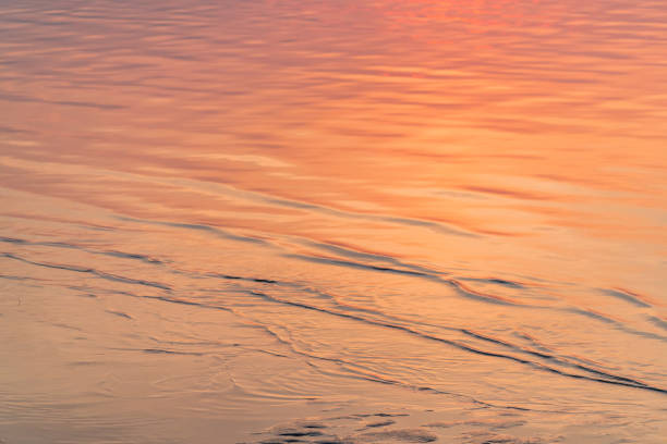 istock Water surface with waves reflecting orange and red light from sunset 1196866281