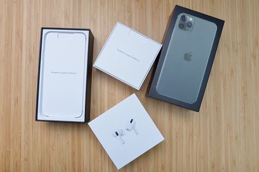 December 27, 2019 - Shanghai, China: Unboxing brand new AirPods Pro and Iphone 11 Pro Max in mid-night green. Studio shot made on wooden table.