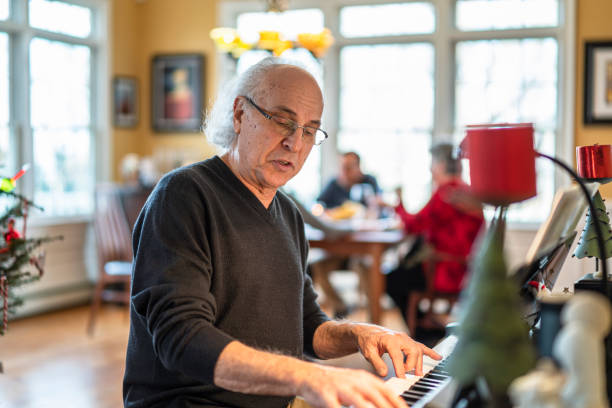 istock Senior man playing piano when his family dinning around a table in the backdrop 1196888657
