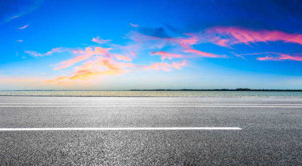 istock Asphalt road and lake with dreamy clouds at sunset. 1196890754