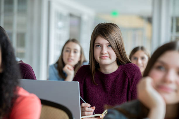 istock High school girl sitting at desk in class and taking notes with a pencil 1196893857