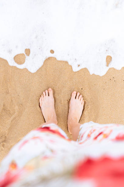 istock Womans feet standing at the beach 1196910033