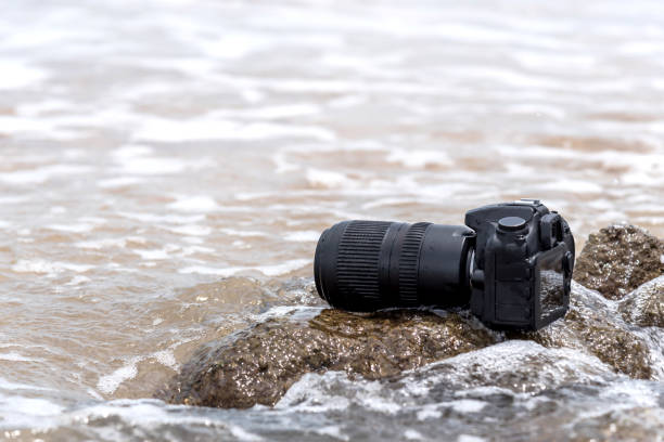 istock DSLR camera on stone beach wet from water sea wave 1196924018