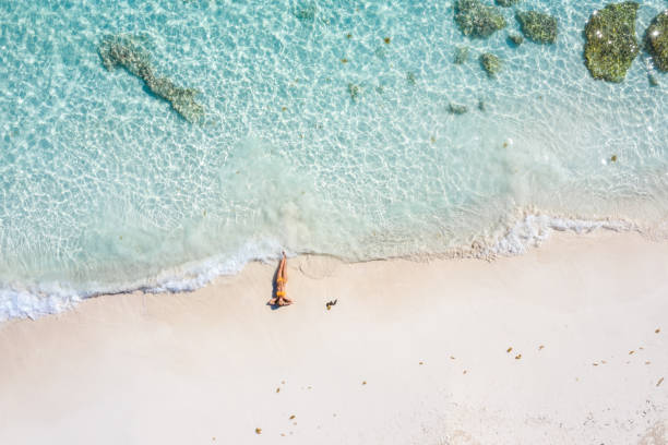 Drone view of woman relaxing on white sand beach stock photo