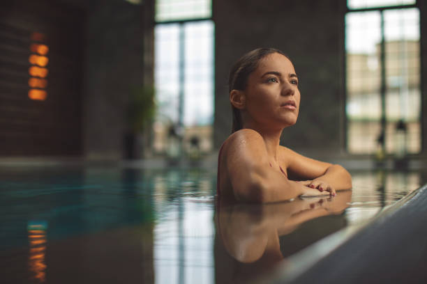 istock Beautiful young woman relaxing on indoors poolside 1196941441