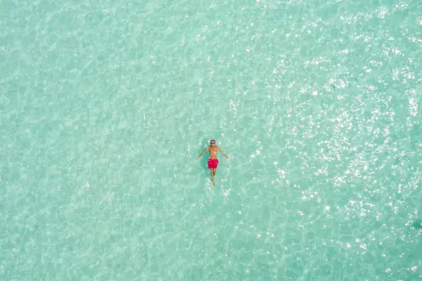 Photo of Drone view of man relaxing on tropical sea floating on water