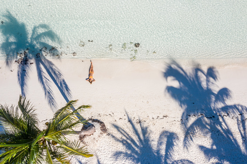 Aerial shot of young woman lying down on tropical beach, Mexico\nShot with drone, directly above.