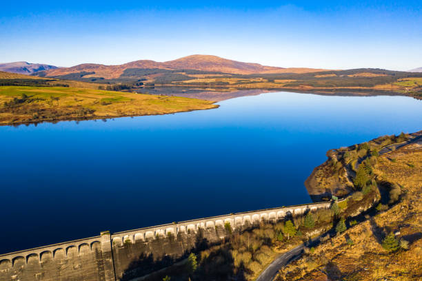 Aerial view of a Scottish loch and dam in Dumfries and Galloway, south west Scotland An aerial view, captured by a drone, on a very calm morning of a fresh water reservoir created by building a dam across a Scottish river. The dam was part of the Galloway hydro electric scheme which was built between 1930 and 1936. The loch is in part of the country popular for walking and mountain biking. Galloway Hills stock pictures, royalty-free photos & images