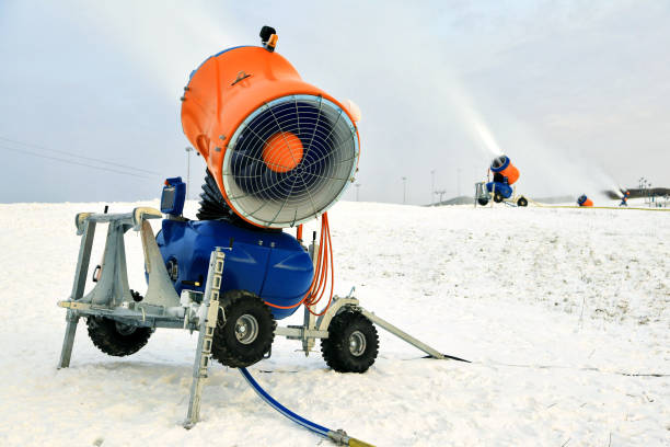 Snow-machine bursting artificial snow  over a skiing slope to alow for the skiing season to start