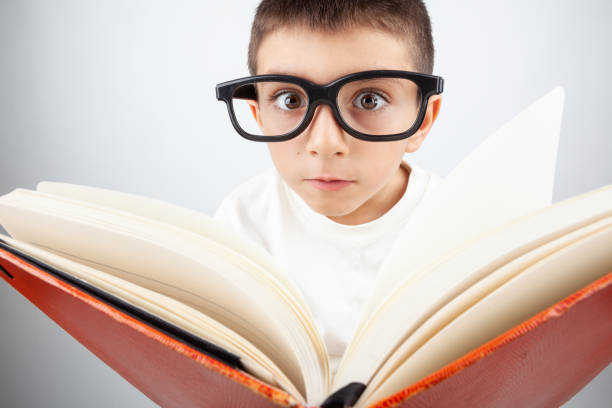 retrato de seis años niño leyendo un gran libro - eyewear child glasses 6 7 years fotografías e imágenes de stock