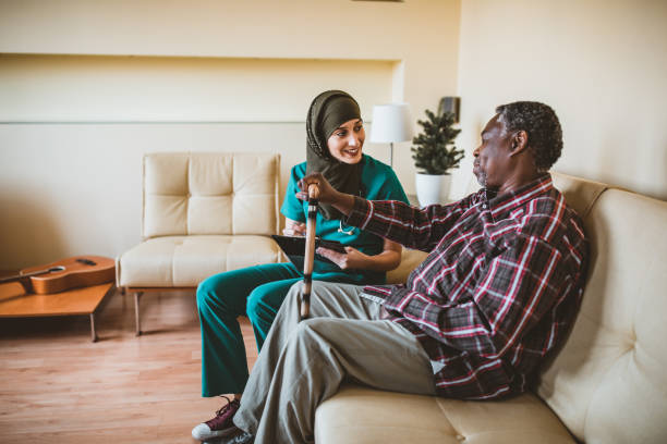 close-up do homem sênior de sorriso com vara de passeio e enfermeira amigável. cuidador amigável que fala com um homem idoso feliz com uma vara de passeio em um sanatório. um médico muçulmano do sexo feminino e seu paciente afro-americano sênior - nurse ethnic doctor real people - fotografias e filmes do acervo