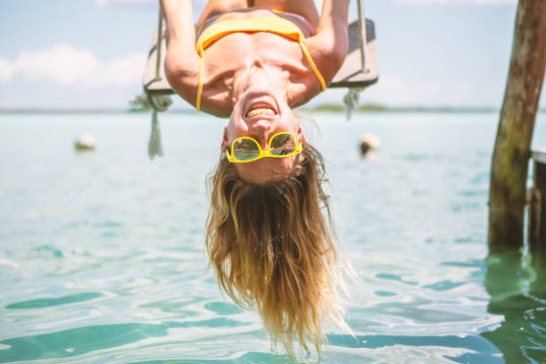 ragazza capovolta che gioca in altalena sul mare, messico - offbeat foto e immagini stock