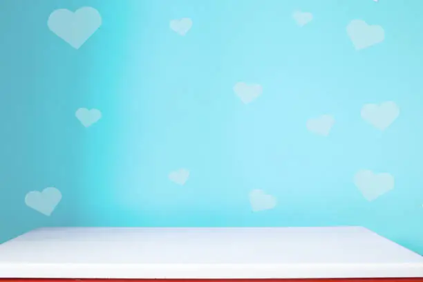 Photo of empty white table on the blur blue heart wall background