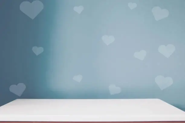 Photo of empty white table on the blur dark blue heart wall background