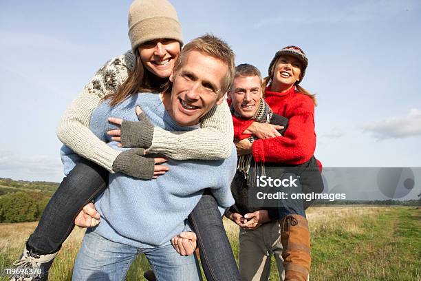 Dos Parejas Que Piggyback Ride Al Aire Libre Foto de stock y más banco de imágenes de 40-49 años - 40-49 años, Otoño, Parejas