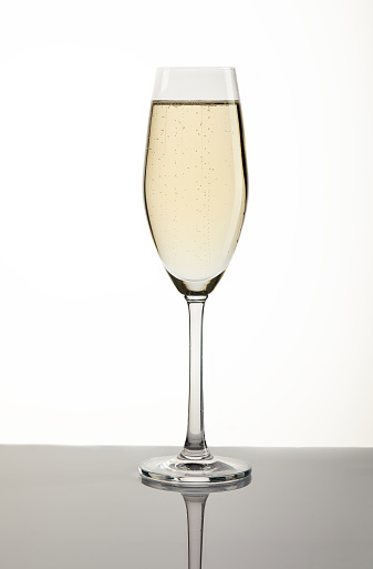 Glass with champagne on a white background with a gray substrate.