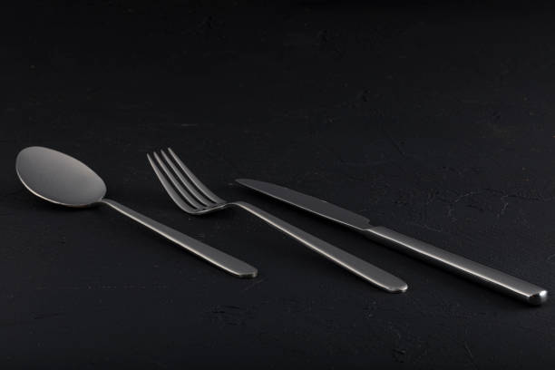 istock Abstract image of knife, spoon and fork on dark background. 1196970995