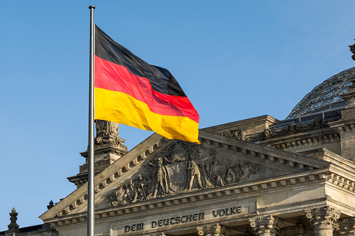 Bandera alemana revoloteando frente al edificio del Reichstag. Berlín, Alemania photo