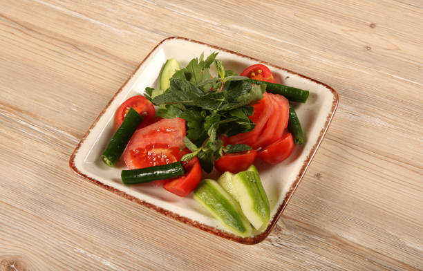 Green vegetables and tomato salad on wooden table