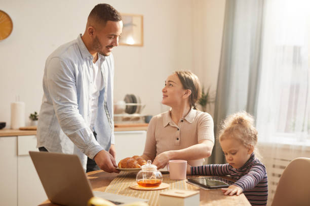istock Modern Family Using Gadgets at Breakfast in Cozy Kitchen 1196980267