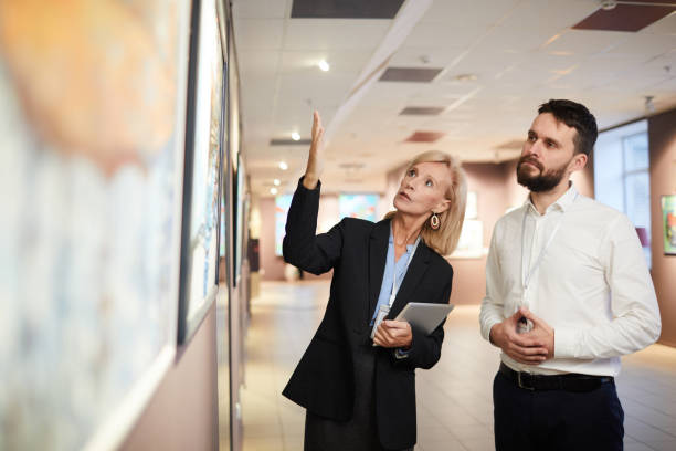 istock Experts Discussing Paintings in Art Gallery 1196980546