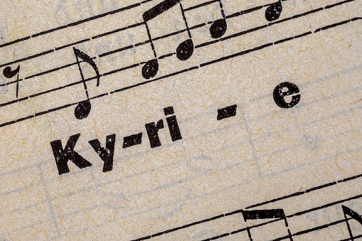 printed word Kyrie on old handmade paper with music notes