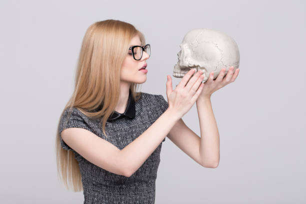 istock Young blonde smart woman caress skull 1196984556