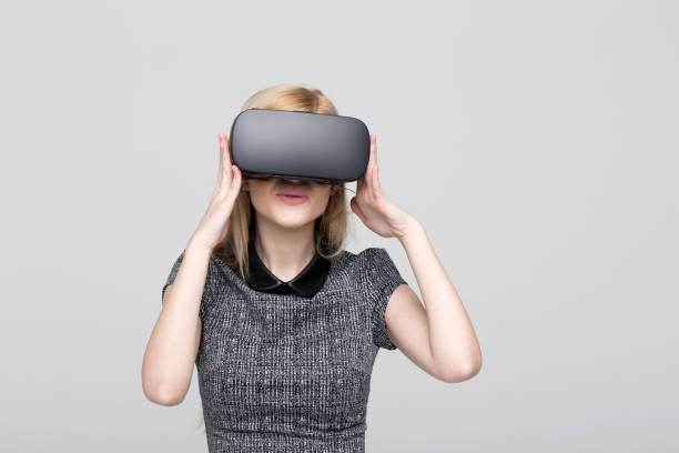 istock Young blonde woman using VR headset on grey background 1196986237