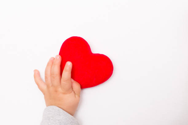 istock red heart in the children's arm, white background 1196996531