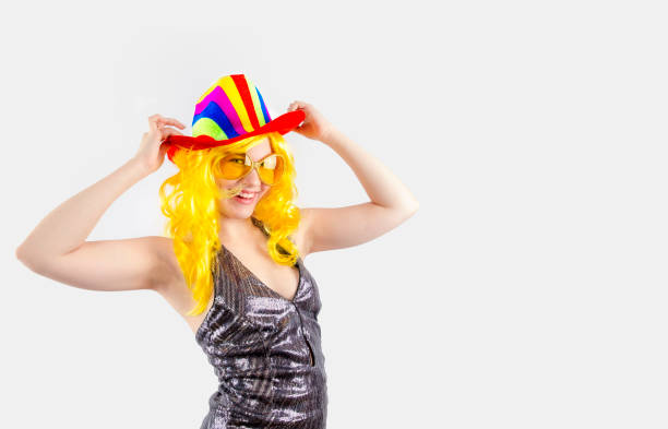 istock A young lady in a multi-colored carnival cowboy hat, carnival glasses is looking at the camera. Isolated on a gray background. Copy pace 1196997364