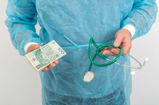 стокові фото, фото роялті-фрі та зображення на тему лікар тримає купу польських грошей банкнотами і стетоскопом. фінансова концепція медичних послуг - зарплата сімейного лікаря в україні 2020