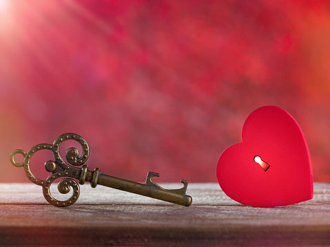 Valentine's day concept. Small rustic red heart with old key on wooden table