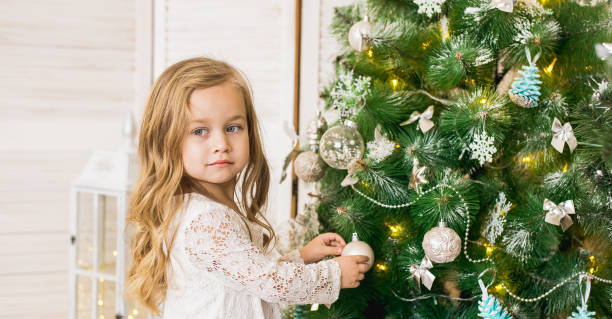 istock happy girl decorates the Christmas tree 1197004308