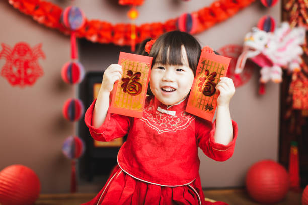 伝統的なドレスアップを持つ中国の女の子は、中国の新年を祝う - hong bao ストックフォトと画像