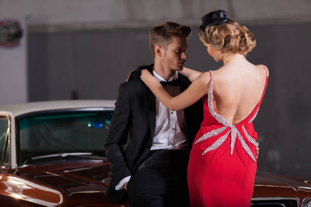 jeune couple d'élégance au garage avec sa voiture rétro - haute couture beautiful smoking beauty photos et images de collection